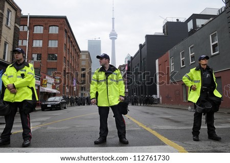 TORONTO-JUNE 26:   A group of Toronto police officers standing in front of a perimeter formed by the riot police during the G20 Protest on June 26 2010 in Toronto, Canada.
