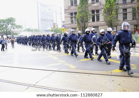 TORONTO-JUNE 26:  Riot police group marching on the streets  after a police car was torched nearby during the G20 Protest on June 26, 2010 in Toronto, Canada.