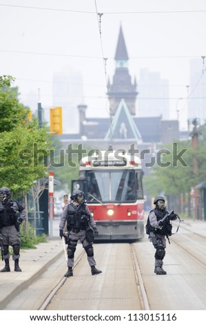 TORONTO-JUNE 27: Police personnel with gas masks protecting the street cars from getting vandalized during the G20 Protest on June 27, 2010 in Toronto, Canada.