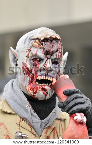 TORONTO-OCTOBER 20:A participant with fake blood and teeth trying to bite fake human hand during the Halloween parade on October 20, 2012 in Toronto, Canada.