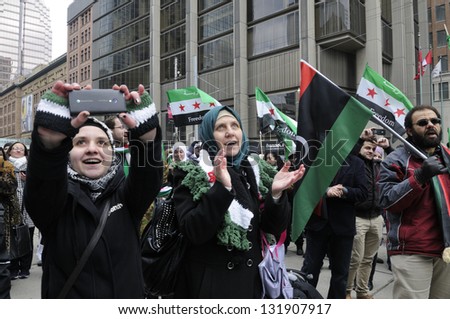 TORONTO-MARCH 16: Syrians taking pictures and clapping during a protest rally organized to raise awareness and commemorate two years of Syrian revolution on March 16, 2013 in Toronto, Canada.
