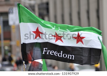 TORONTO-MARCH 16 A protester waiving a Syrian flag during a protest rally organized to raise awareness and commemorate two years of Syrian revolution on March 16 2013 in Toronto Canada TORONTO-MARCH 16 A protester waiving a Syrian flag during a protest rally organized to raise awareness and commemorate two years of Syrian revolution on March 16 2013 in Toronto Canada