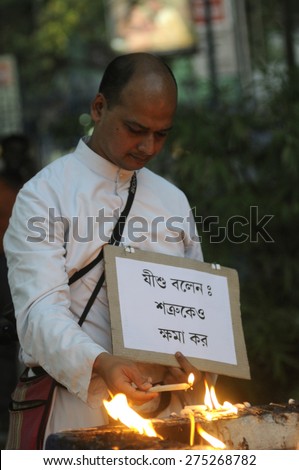 KOLKATA - MARCH 16 : A Christian priest lighting candles with a sign asking for forgive ness during a candle light vigil to protest gang rape of an elderly nun on March 16, 2015 in Kolkata, India.