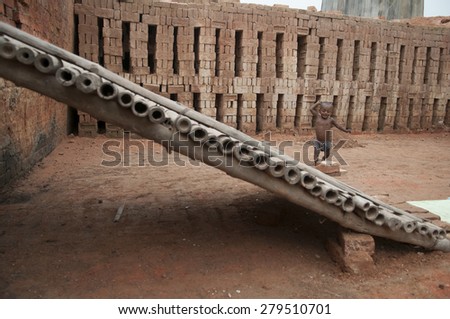 KOLKATA -OCTOBER 26 :A small kid whose parents work in the brick industry under  tough conditions playing inside the factory before the production season begins on October 26, 2014 in Kolkata,India.