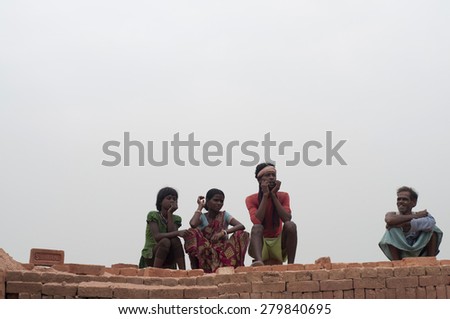 KOLKATA - OCTOBER 26 : Group of brick factory workers sitting on stacks of bricks inside a brick factory where they stay and work under unhealthy conditions on October 26, 2014 in Kolkata , India.