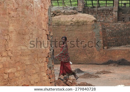 KOLKATA - OCTOBER 26: A woman worker passing by inside a brick factory where she work and stay under difficult conditions  on October 26,2014 in Kolkata,India.