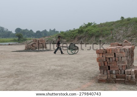 KOLKATA - OCTOBER 26 : A worker carrying bricks from  where they work for minimum wage and without any kind of social security on October 26, 2014 in Kolkata , India.