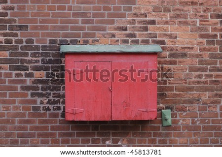 An old and closed electrical box on a brick background outside an old company building.