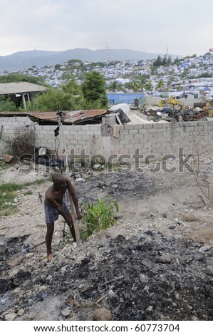 PORT-AU-PRINCE - AUGUST 28: A man trying to lift a pole ,in order to take it to some other place to built another tent for his family,  on August 28, 2010 in Port-Au-Prince, Haiti