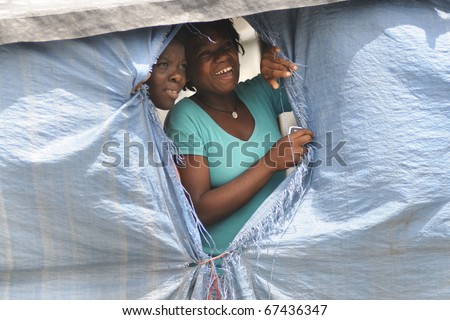 PORT-AU-PRINCE - SEPTEMBER 1:Camp residents peeping out through their tent window to watch a rally passing,  in Port-Au-Prince, Haiti on September 1, 2010.