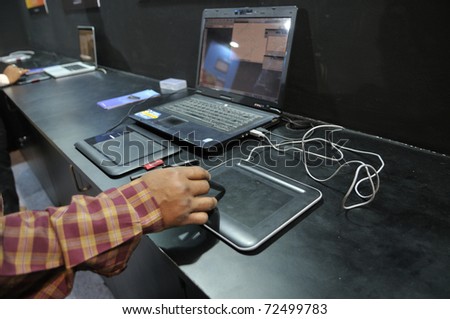 KOLKATA- FEBRUARY 20: A  man tries to use the pen & touch pad, during the Information and Communication Technology (ICT) conference and exhibition in Kolkata, India on February 20, 2011.