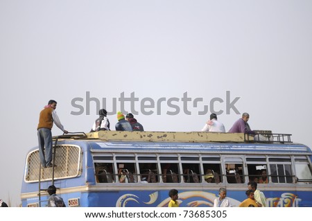 KENDULI - JANUARY 14: People climbing on the roof of a bus to travel as there is less space inside the bus- an example of growing population in India,in Kenduli ,India on January 14, 2011.