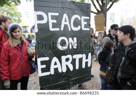 TORONTO - OCTOBER 15:  People stopping near a sign to have a closer look at the sign which urges for a peaceful world during the Occupy Toronto Movement on October 15, 2011 in Toronto, Canada.