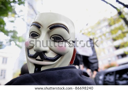 TORONTO - OCTOBER 15: A protestor listens to the speeches with his mask  tied to his shoulder during the Occupy Toronto Movement on October 15, 2011 in Toronto, Canada.