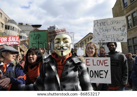 TORONTO - OCTOBER 17: A protestor wearing a guy fawkes mask  walking in a rally  during the Occupy Toronto Movement on October 17, 2011 in Toronto, Canada.