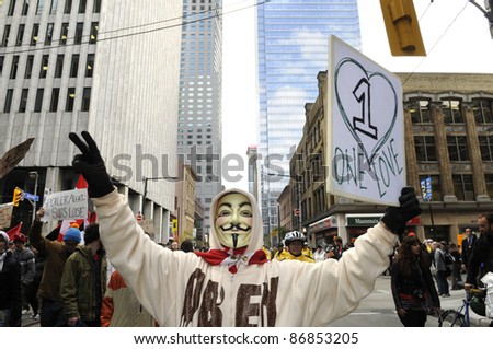 TORONTO - OCTOBER 17: A protestor wearing a guy fawkes mask walking in a rally  with placards during the Occupy Toronto Movement on October 17, 2011 in Toronto, Canada.