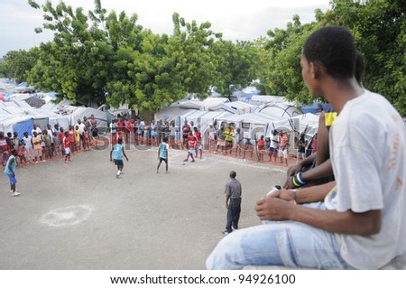 PORT-AU-PRINCE - AUGUST 26: An unidentified teen watching  a local friendly soccer match from a nearby rooftop  in Port-Au-Prince, Haiti on August 26, 2010.