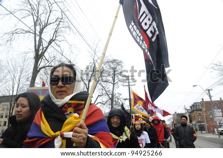 TORONTO - MARCH 10: An unidentified woman holding a Tibetan Resistance  flag marching in a rally organized to protest against the Chinese occupation of Tibet on March 10 2009 in Toronto, Canada.