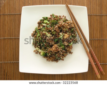 quinoa salad with broccoli, tofu, cilantro, and sesame ginger dressing on a white squared china plate placed on a bamboo matte