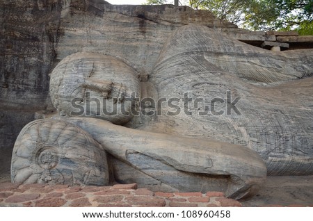 POLONNARUWA, SRI LANKA - MAY 19: Reclining Buddha facade on May 19,2012 in Polonnaruwa,Sri Lanka.  Reclining Buddha at rock temple was carved into the face of a large granite rock.