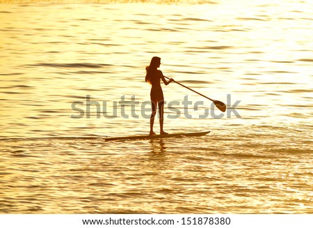 Silhouette Of Woman Paddleboarding At Sunset, Malibu, California, Recreation Sport Paddling Ocean Beach Surf Orange Sunlight Reflection Hue On Water