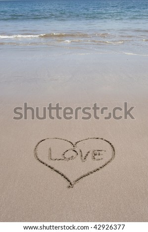 tropical beach scene with blue water and love heart with word love written in the sand