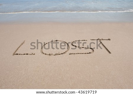 the word lost written in sand on tropical beach near water in big letters