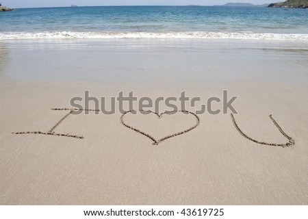 letters written in sand on  costa rican tropical beach symbol and letters say i love u near blue water