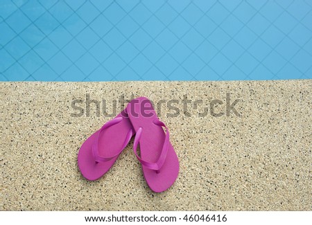 pink shoes near edge of swimming pool with calm blue water