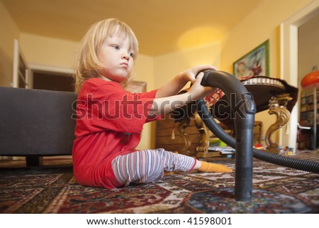boy with long blond hair helping with vacuum cleaning