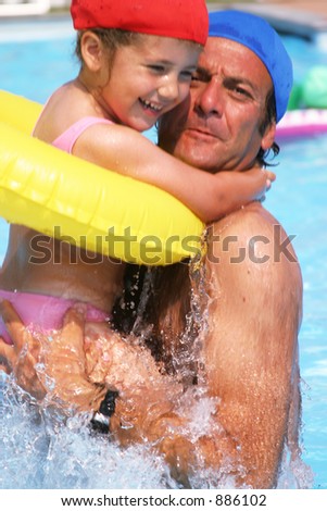 father and daughter having fun in the pool- focus on the splash