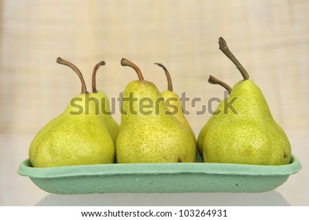 six pears in a green carton plate