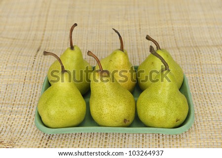 six pears in a green carton plate