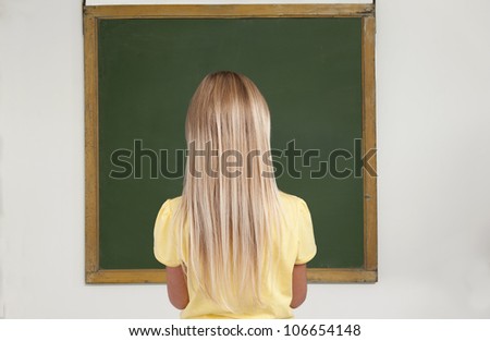 girl standing in front of an old chalkboard in a classroom