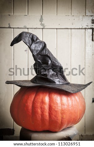 halloween witch hat on pumpkin lying on straw