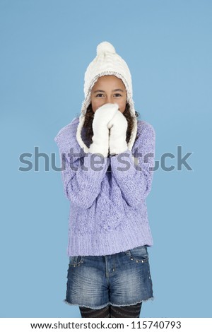 Girl with winter hat and gloves on blue background