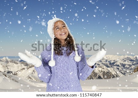 snowing on girl with winter hat and gloves, mountains in background