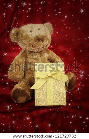 Teddy bear with golden gift box on red background with stars