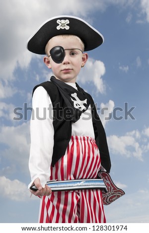 young boy in pirate costume outdoors against a clouds background