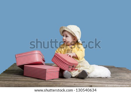 little baby girl with vintage suitcases on an old wooden raft