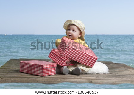 little baby girl with vintage suitcases on an old wooden raft floating in the sea