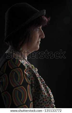 profile of mature woman with hat, isolated on black background