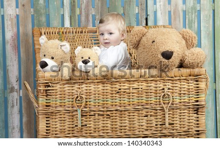 toddler with teddy bears standing in a straw trunk
