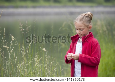 young girl outdoors playing with grass sprites