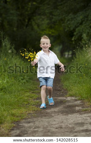 Mother\'s day : little boy with flowers in his hands running on a path in the woods
