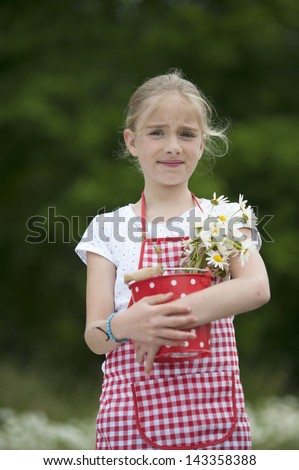 girl with red and white checkered apron and bouquet of daisies outdoors