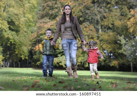 Mother and children walking in the park in autumn