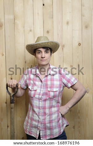 adult woman with cowboy hat leaning against a wooden wall