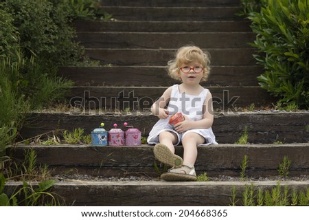 little girl seated on old wooden stairs with musical boxes