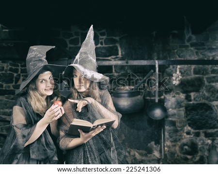 two halloween witches whispering a magic formula to poison an apple